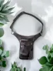 Brown leather sling bag with a detachable strap, silver hardware, and blue zipper, placed on a marble surface. It exudes a rugged yet stylish tone.
